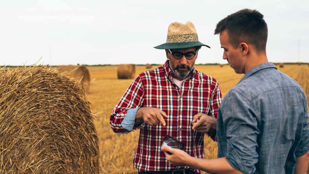 Zwei Männer unterhalten sich im Freien auf einem kultivierten Weizenfeld.