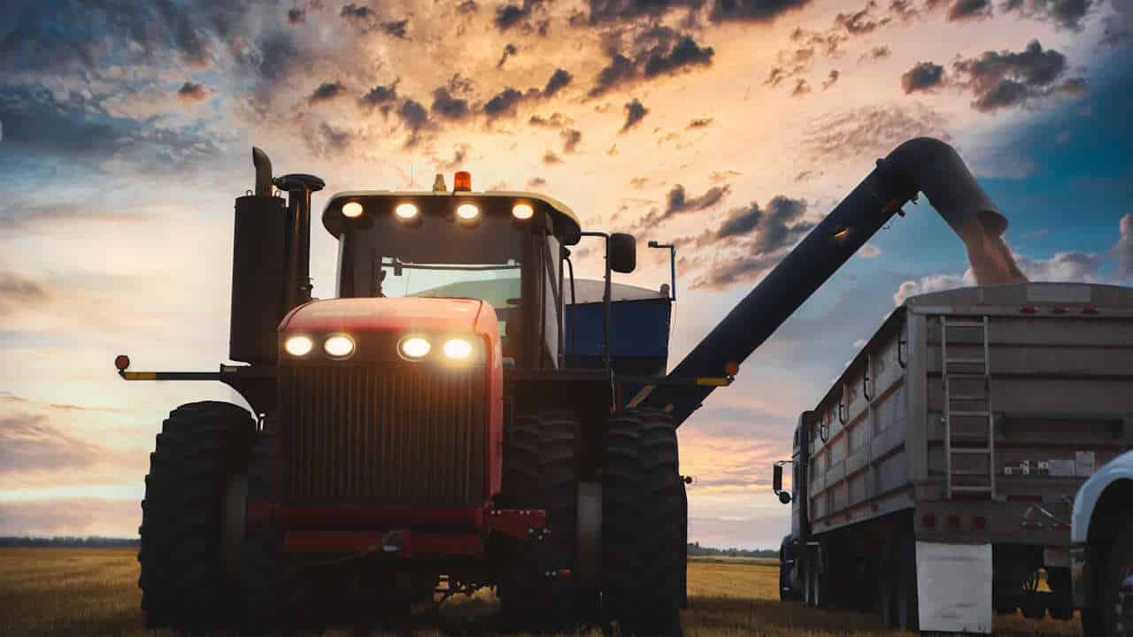 Ein Traktor mit einem Getreidewagen, der Weizen in einen Sattelzug entlädt