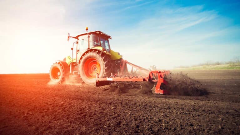 Ein Traktor arbeitet bei Sonnenuntergang auf dem Ackerland.