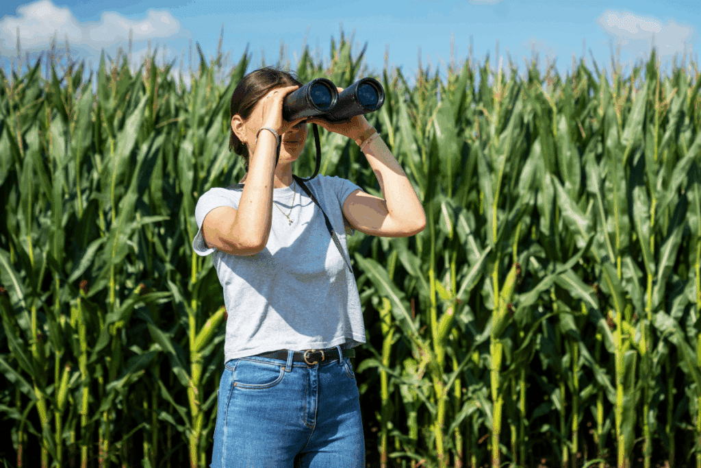 Frau mit Fernglas vor einem Feld