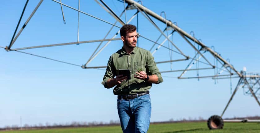 Mitarbeiter eines Agrarunternehmens kontrolliert Pflanzen auf einem Feld mit Tablet.